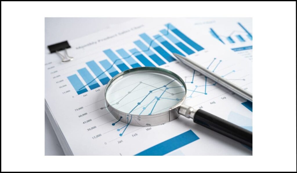 Lupa sobre gráficos de barras y líneas en un informe de ventas, representando el análisis de datos y la importancia de transmitir información visual de manera accesible.
