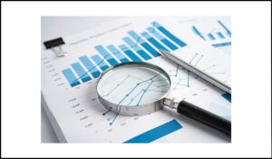 Lupa sobre gráficos de barras y líneas en un informe de ventas, representando el análisis de datos y la importancia de transmitir información visual de manera accesible.