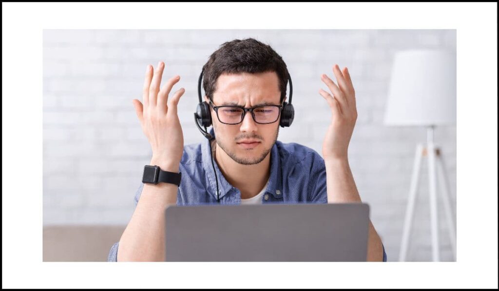 Hombre con audífonos frente a un portátil, mostrando frustración debido a la reproducción automática de sonido sin opción de apagado, representando un problema de accesibilidad web.