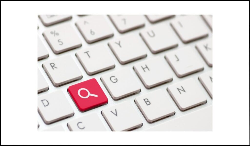 Teclado de computadora con la tecla "D" resaltada en rojo con un icono de lupa, simbolizando un atajo de teclado para búsqueda.